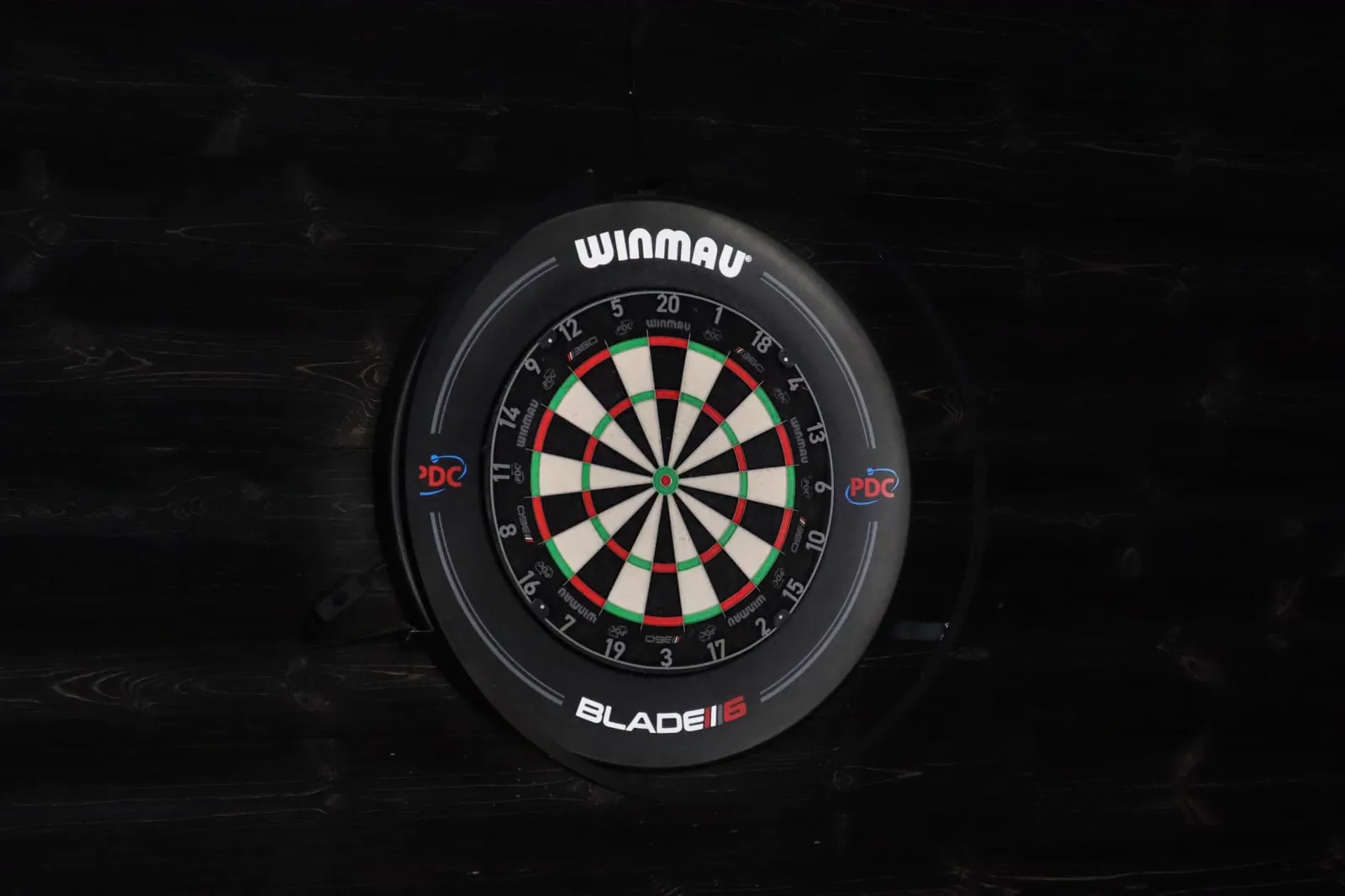 Winmau-darttavla på mörk trävägg
